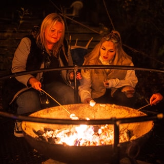 Two people roasting marshmallows over a fire pit at Marshmallowland