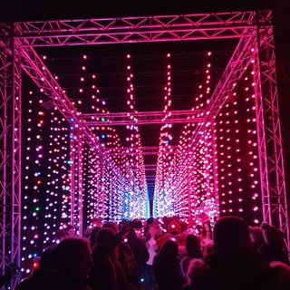 Large crowd gathering under a roof of light strings dangling from above